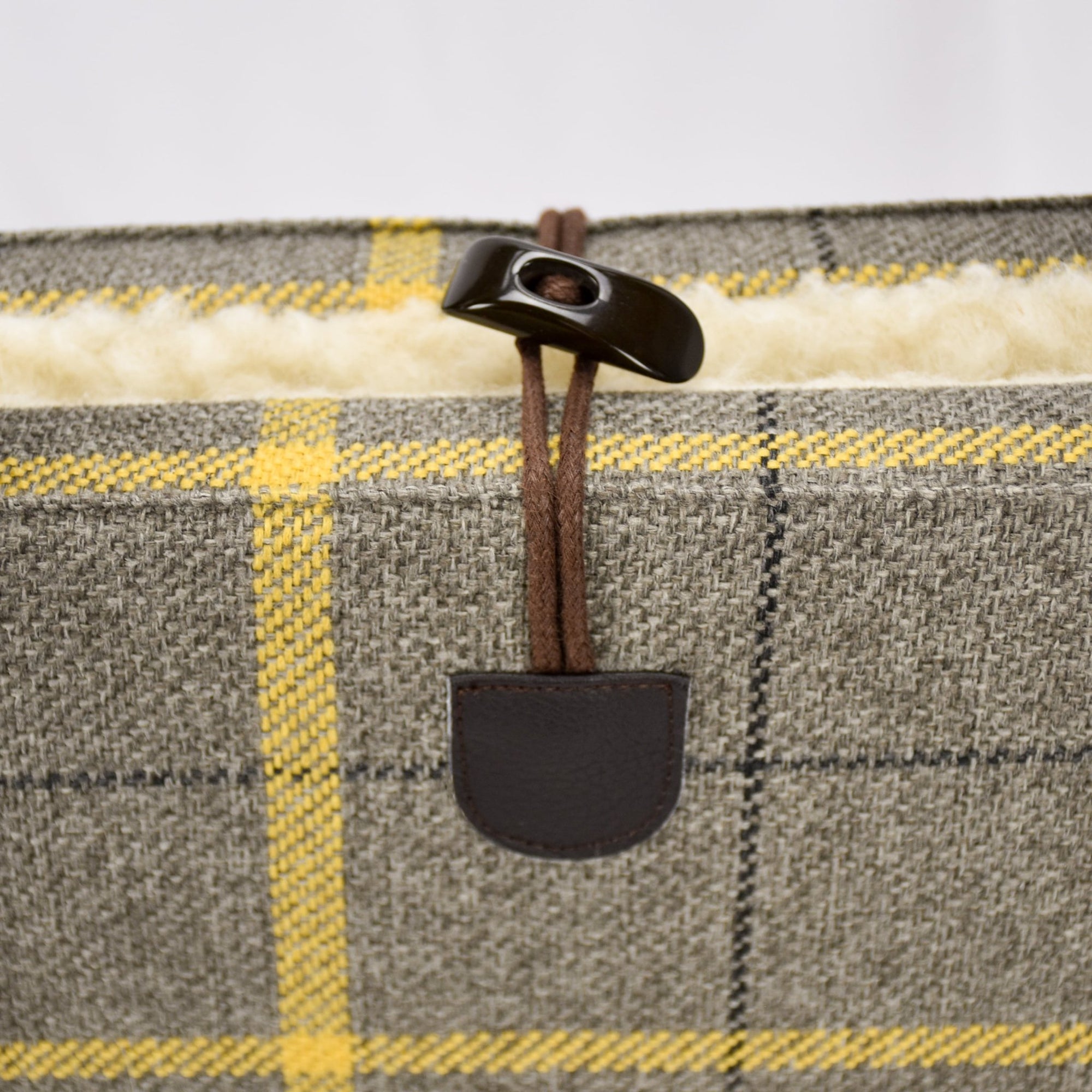 Detail of the plaid portable dog bed with a toggle closure by  KONA CAVE®.